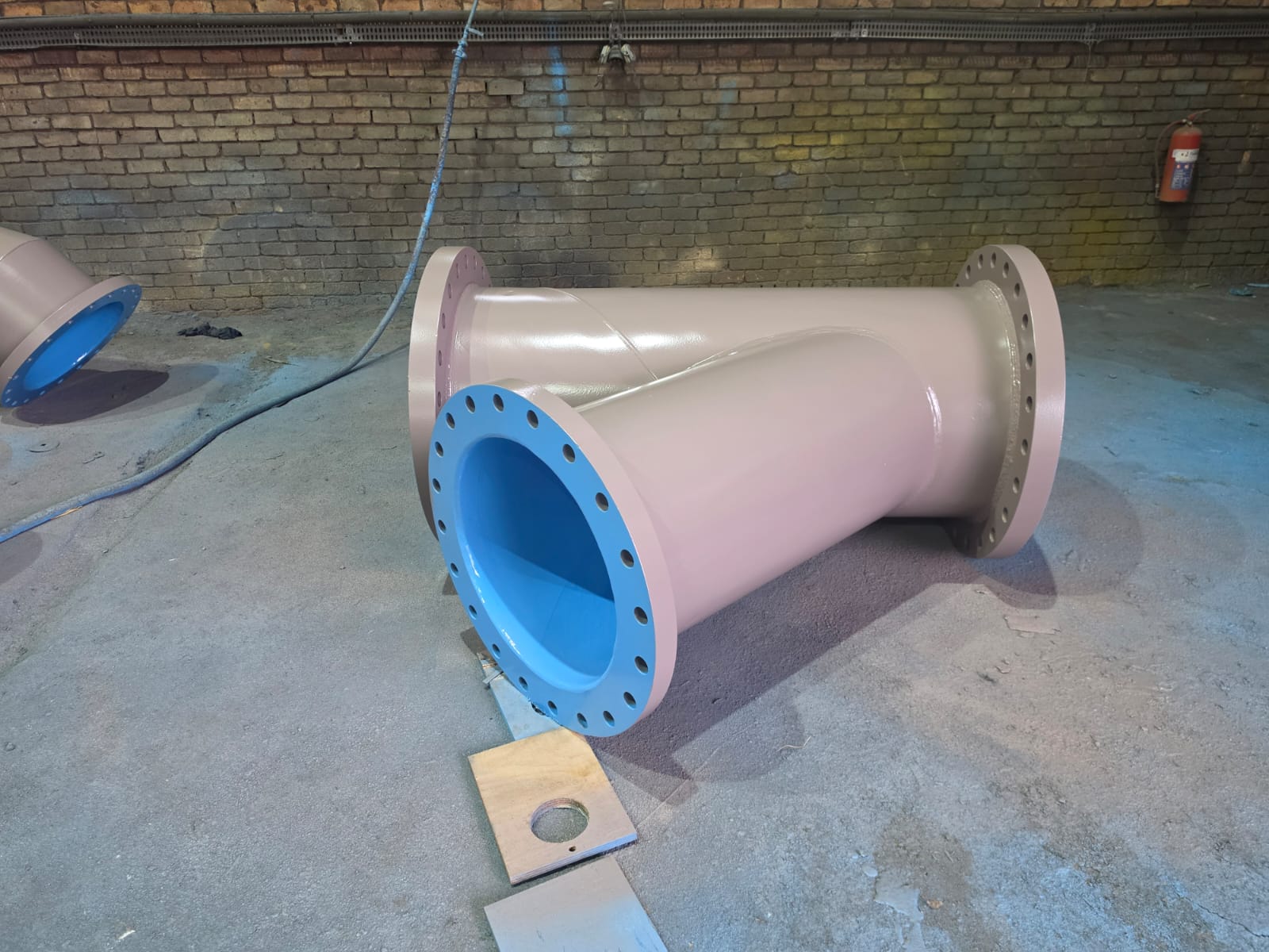 Epoxy-lined steel tee fitting with flanged ends for slurry pipeline systems
